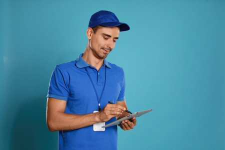 Happy young courier with tablet on blue background. Space for textの写真素材