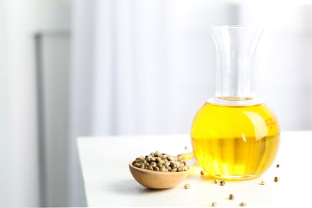 Bottle with hemp oil and seeds on white table indoors. Space for textの写真素材