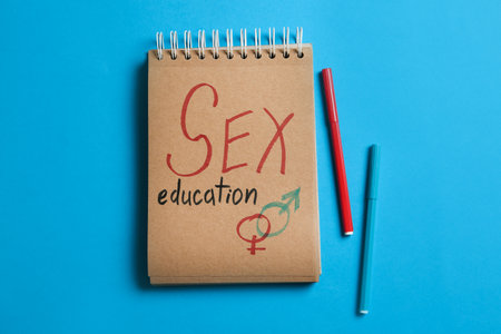 Notebook with phrase "SEX EDUCATION" and gender symbols on blue background, flat layの写真素材