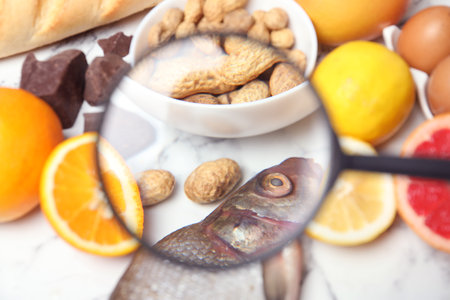 Different products with magnifier focused on fish and peanuts, closeup. food allergy conceptの写真素材