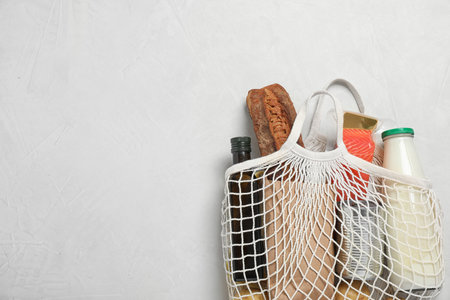 Mesh bag with different products on light gray background, space for textの写真素材