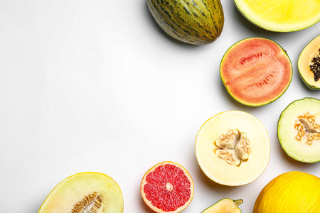 Ripe tasty melons and fresh tropical fruits on white background, top view