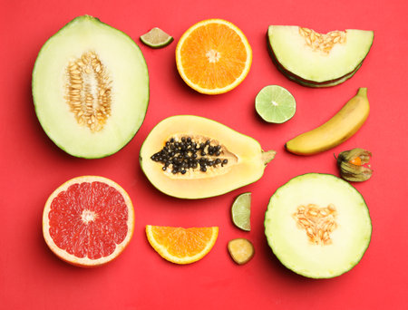 Flat lay composition with tasty melon and fresh tropical fruits on red backgroundの写真素材