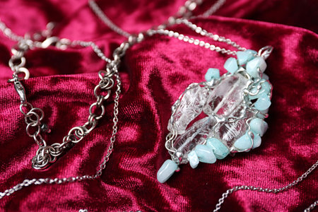 Beautiful silver necklace with pure quartz gemstones on burgundy fabricの写真素材