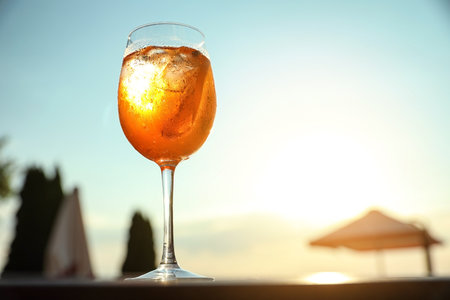 Glass of fresh summer cocktail on table outdoors at sunset, low angle view. Space for textの写真素材
