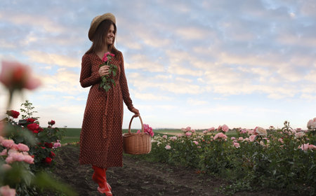 Woman with basket of roses in beautiful blooming field