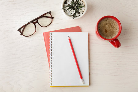Flat lay composition with office stationery and cup of coffee on white wooden tableの写真素材
