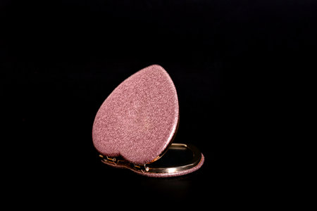 Heart shaped gold pocket mirror on black backgroundの写真素材