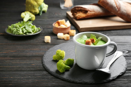 Cup of broccoli cream soup with croutons served on black wooden table, space for textの写真素材