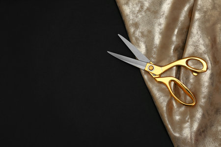 Gold tailor scissors and fabric on black background, top view with space for textの写真素材
