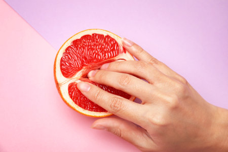 Young woman touching half of grapefruit on color background, above view. sex conceptの写真素材