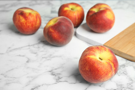 Fresh peaches and wooden board on marble table, space for textの写真素材