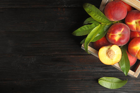 Wooden crate with tasty peaches on black table, top view. Space for textの写真素材