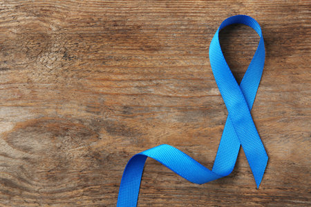 Blue awareness ribbon on wooden background, top view with space for text. Symbol of social and medical issuesの写真素材