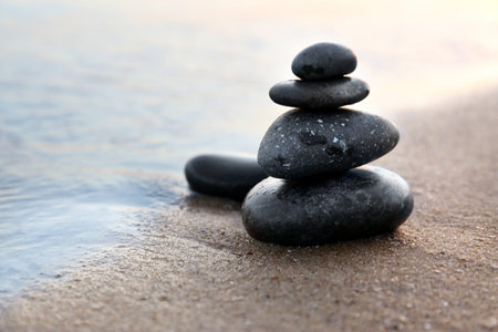 Dark stones on sand near sea at sunset, space for text. Zen conceptの写真素材