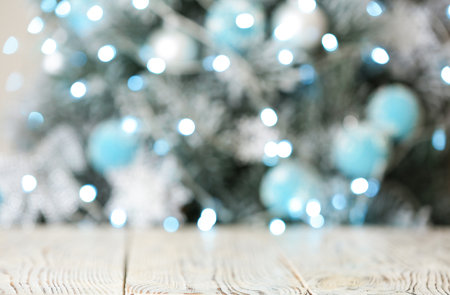 Empty white wooden table and blurred fir tree with Christmas lights on background, bokeh effect. space for designの写真素材