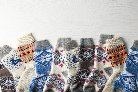 Soft knitted socks on white wooden background, flat lay with space for text. winter clothes