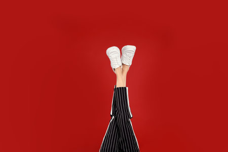 Woman in stylish sport shoes on red backgroundの写真素材