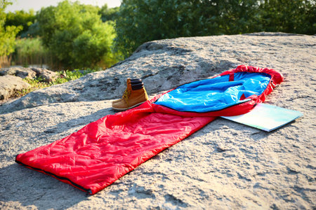 Sleeping bag, boots and map outdoors on sunny dayの写真素材