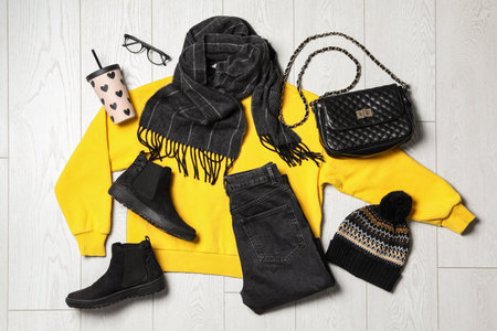 Flat lay composition with winter clothes and boots on white wooden background