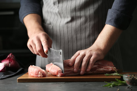 Man cutting fresh raw meat on gray table, closeupの写真素材