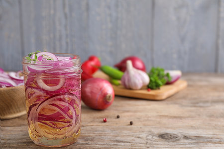 Jar of pickled onions on wooden table, space for textの写真素材