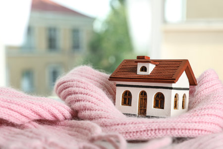 House model and pink scarf on table on blurred background, space for text. heating efficiencyの写真素材