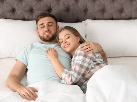Young couple sleeping together in bed at homeの写真素材