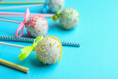 Tasty cake pops and straws on light blue background. Space for textの写真素材