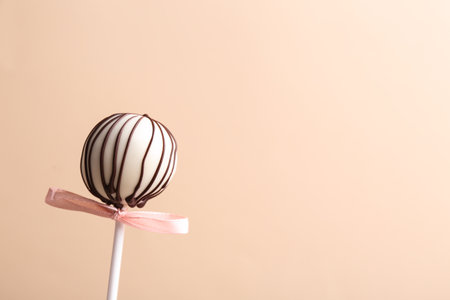 Tasty cake pop with bow on beige background. Space for textの写真素材