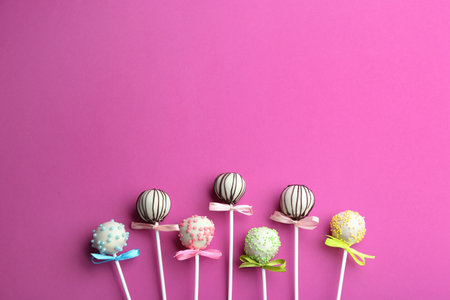 Different tasty cake pops on pink background, flat lay. Space for textの写真素材