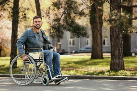 Young man in wheelchair at park on spring dayの写真素材