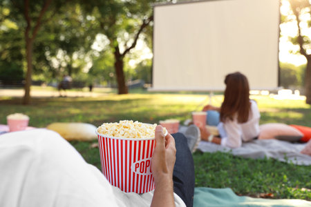 Young man with popcorn watching movie in open air cinema, closeup. Space for textの写真素材