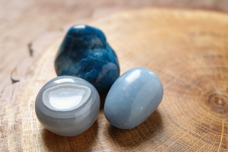 Beautiful blue angelite, gray agate and shattuckite gemstones on wooden stand, closeupの写真素材