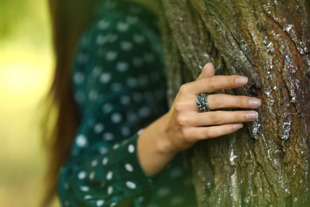Young woman wearing beautiful silver ring with apatite gemstone near tree outdoors, closeupの写真素材