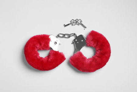 Red furry handcuffs and keys on white background, top view. sex toyの写真素材