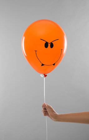 Woman holding spooky balloon for Halloween party on light gray background, closeupの写真素材