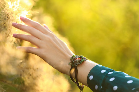 Young woman wearing beautiful metal bracelet with carnelian and gemstones outdoors, closeup
