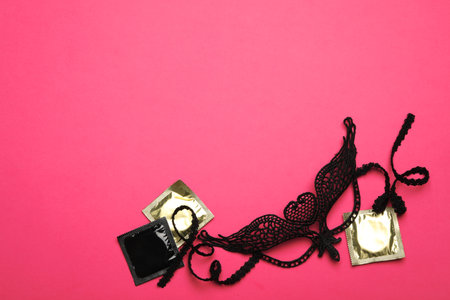 Lace mask and condoms on pink background, top view with space for text. sex gamesの写真素材