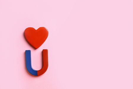 Red and blue horseshoe magnet with heart on pink background, flat lay. Space for textの写真素材