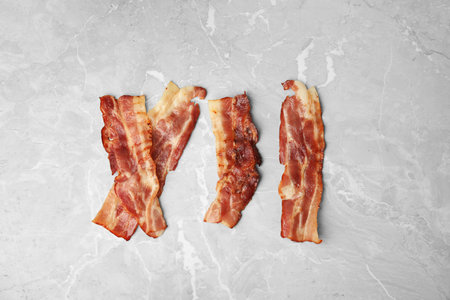 Slices of tasty fried bacon on light gray marble table, flat layの写真素材