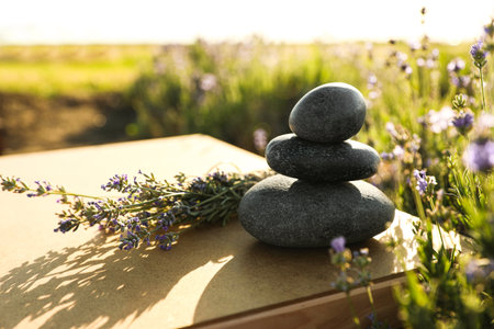 Stack of spa stones on wooden table in lavender field. Harmony and zen