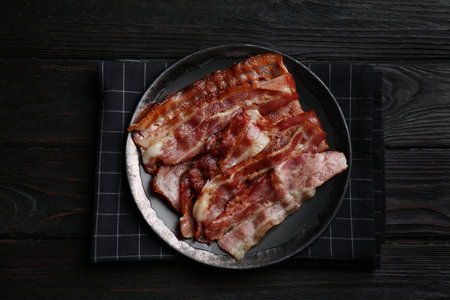 Slices of tasty fried bacon on black wooden table, top viewの写真素材