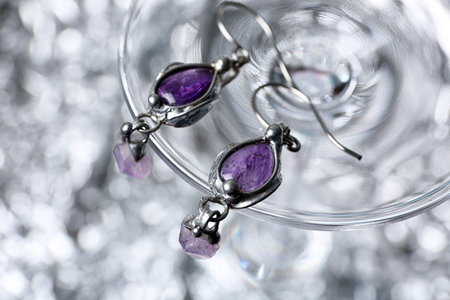 Closeup of beautiful pair of silver earrings with amethyst gemstones on blurred backgroundの写真素材
