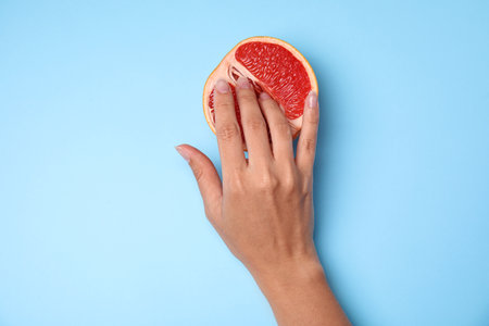 Young woman touching half of grapefruit on blue background, top view. sex conceptの写真素材