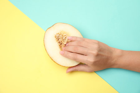 Young woman touching half of melon on color background, top view. sex conceptの写真素材