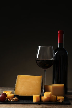 Delicious cheese served with red wine on table against dark backgroundの写真素材