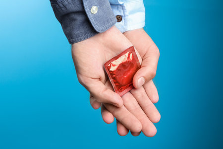Gay couple with condom on light blue background, closeupの写真素材