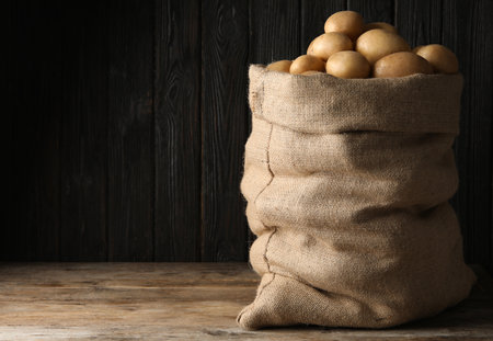 Raw fresh organic potatoes on wooden table against dark background. Space for textの写真素材