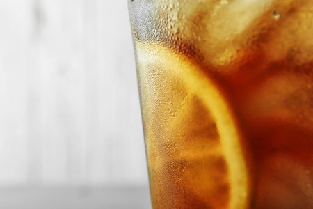 Glass of refreshing iced tea against light background, closeup. Space for textの写真素材